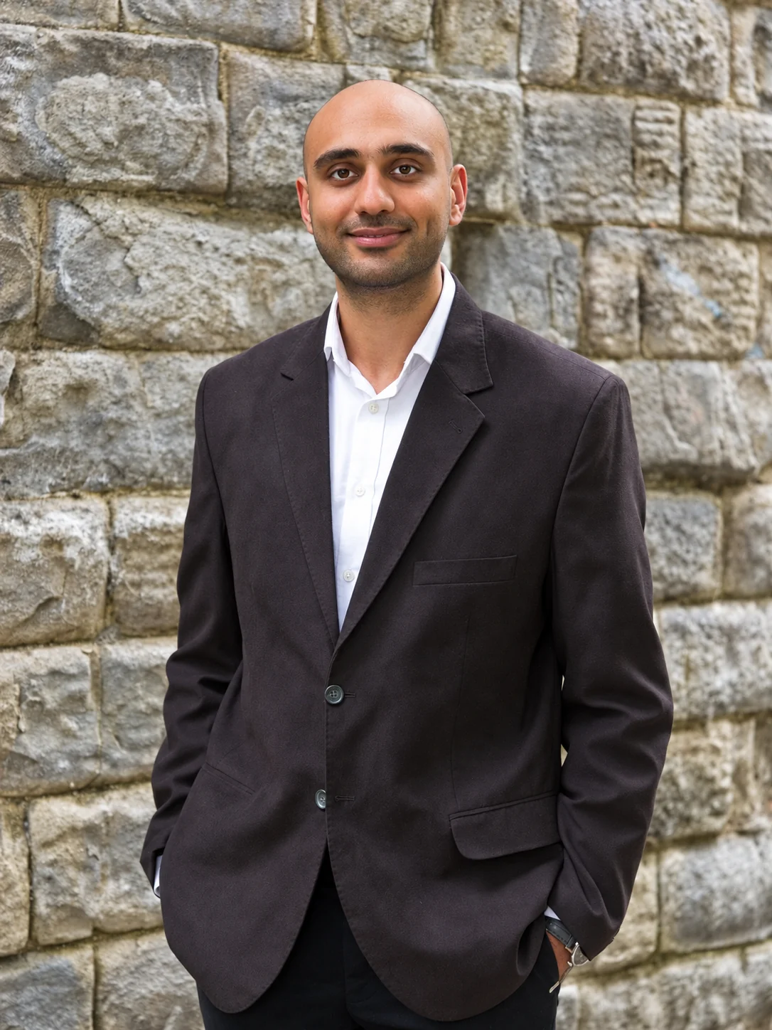 Adel Moin standing in front of a stone wall