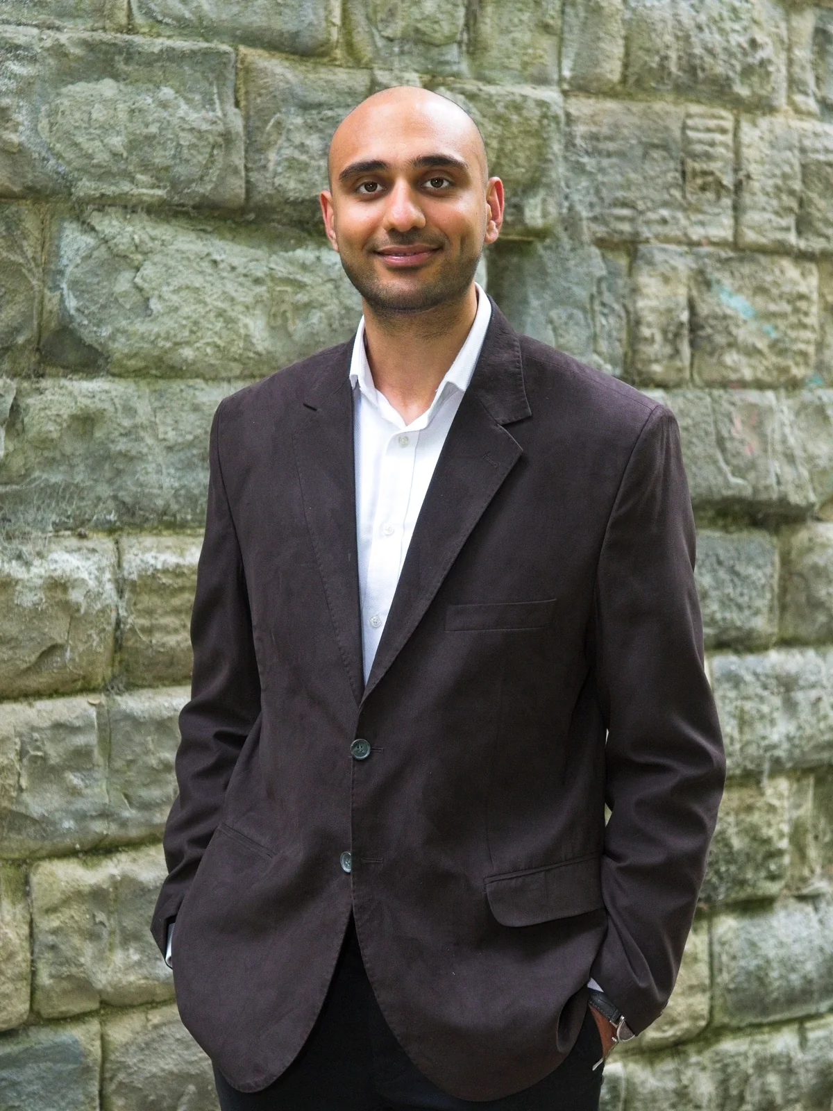 Adel Moin standing in front of a stone wall