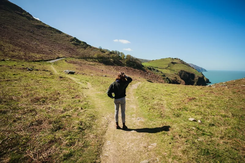 A person standing where a coastal footpath branches in two directions