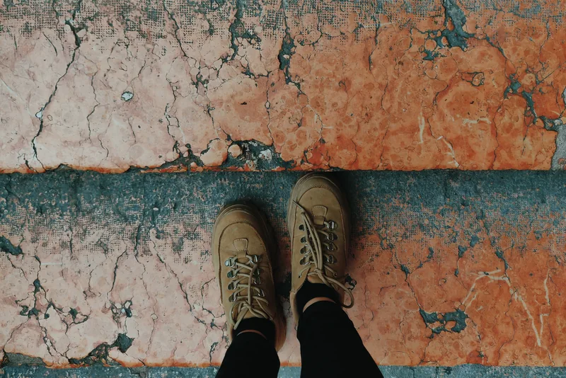 Walking boots on a worn orange and grey pavement