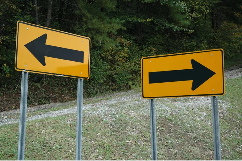 Two yellow direction signs pointing in opposite directions