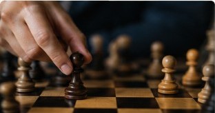 A hand moving a chess piece on a board