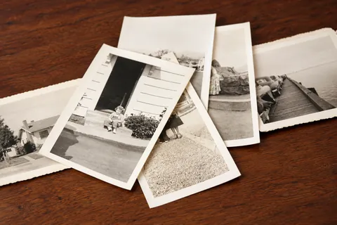 Old black-and-white family photographs spread on a wooden table