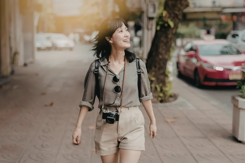 A woman with a camera walking along a city street