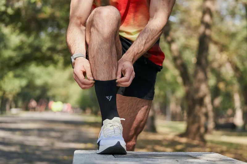 A runner adjusting a sock before a run outdoors